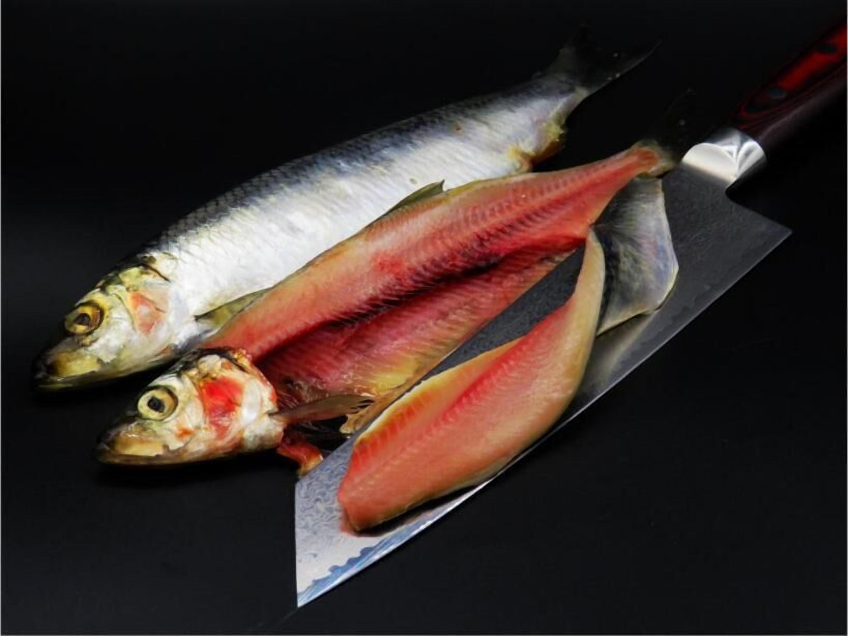 Drei Fische auf einer schwarzen Oberfläche mit einem großen Messer.