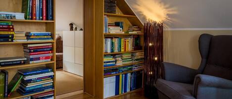 Un rincón acogedor para leer con una estantería llena de libros, un sillón cómodo y una lámpara original.