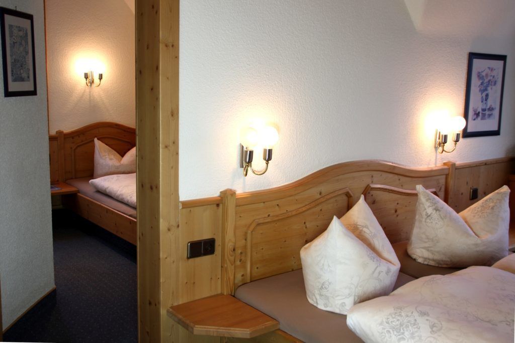 A wooden bed with a headboard and two wall-mounted light fixtures.