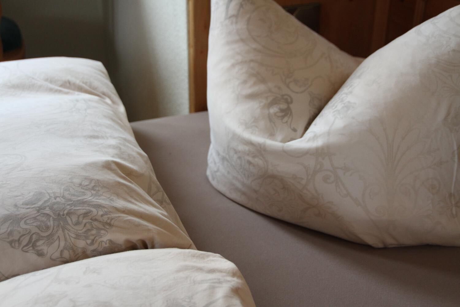 A close-up of a bed with patterned pillows and a neutral-toned mattress.