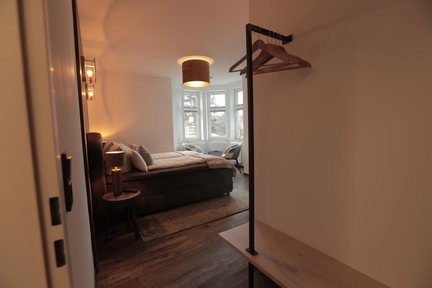 Ein Schlafzimmer mit Bett, Nachttisch, Lampe und einer Pendelleuchte.