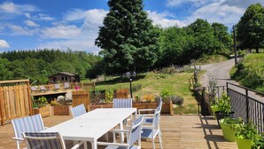A wooden deck with a white table and striped chairs, surrounded by potted plants and a wooden fence. - Le Moulin de la Fortie (Viscomtat)