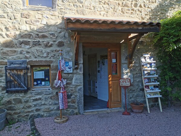 A stone building with a rustic entrance, a signboard, and a display of books.