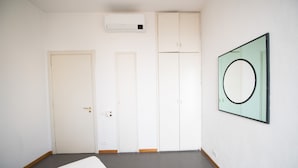 A room with a bed, a wardrobe, a door, and an air conditioning unit.