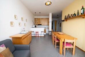 A modern kitchen with wooden cabinets, a dining area with a wooden table and chairs, and a small island with stools.