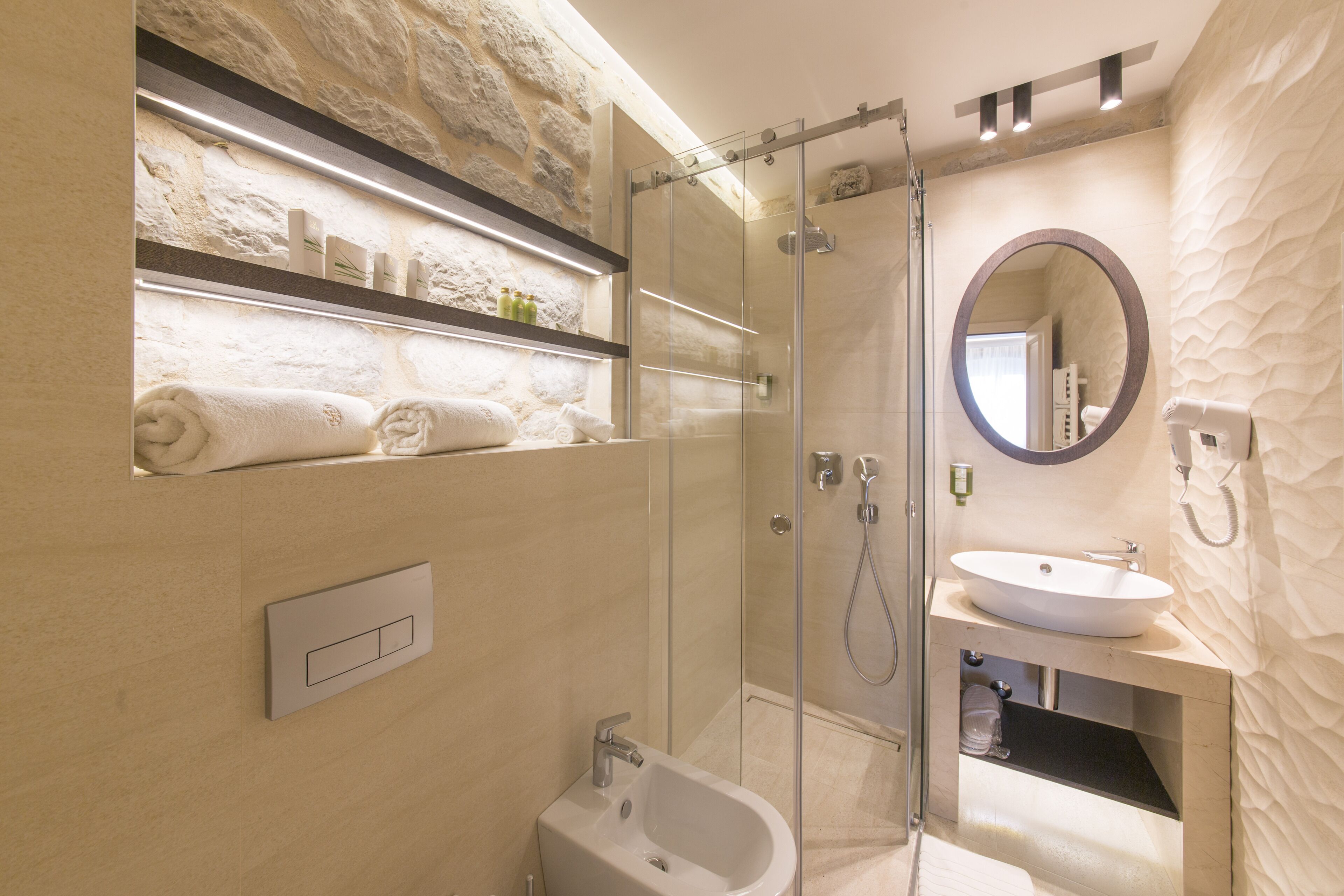 A modern bathroom with a glass-enclosed shower, a built-in sink, and a towel rack with neatly folded towels.