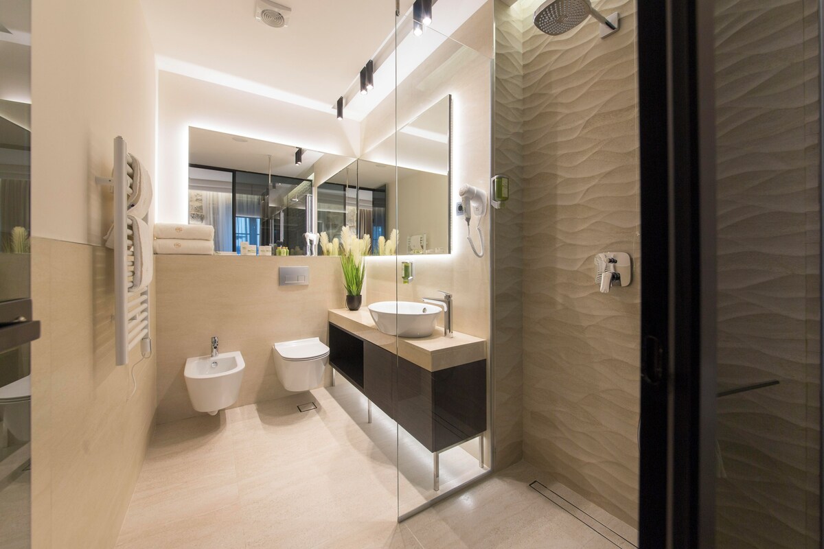 Un baño moderno con un bidé, un lavamanos, un espejo y una zona de ducha.