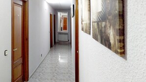 A hallway with wooden doors, a radiator, and a framed picture on the wall. - Hostal Lady Ana Maria (Collado Villalba)