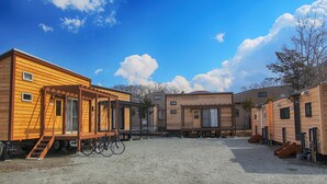 Una hilera de casas móviles de madera con escaleras exteriores y una bicicleta estacionada adelante.