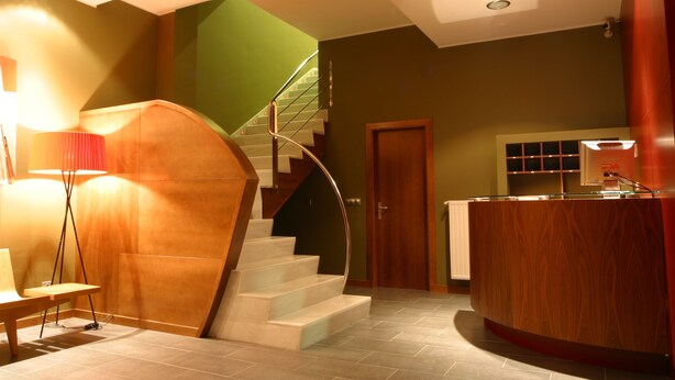 Un intérieur moderne avec un escalier, un comptoir d’accueil et une lampe.
