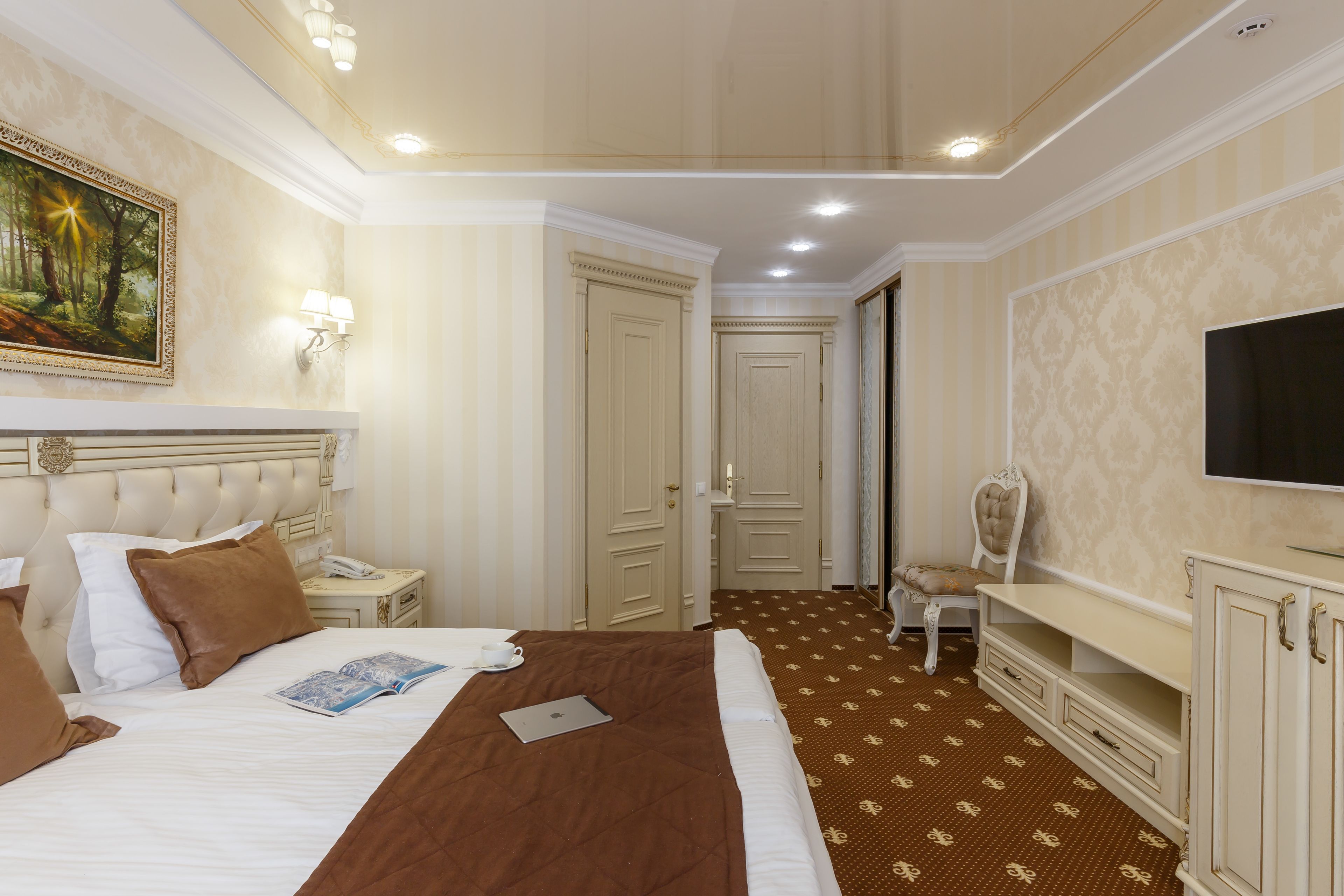 Hotelkamer met een groot bed, een bureau, een stoel, een televisie en een schilderij aan de muur.
