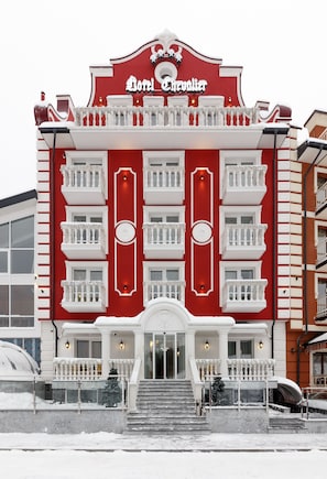 A red and white building with balconies and a sign that reads "Doll's Chandelier." - Chevalier Hotel & Spa (Bukovel)