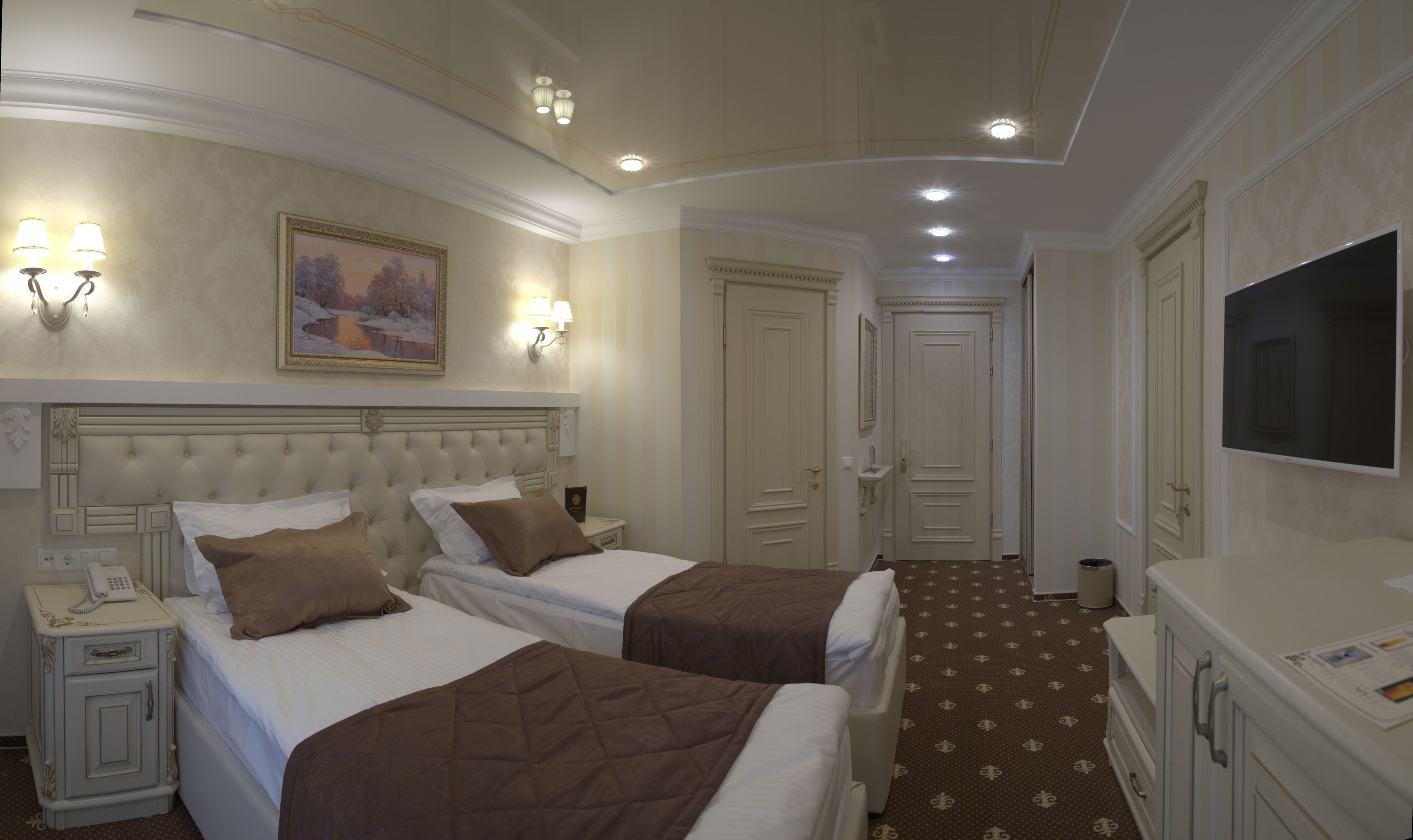 A hotel room with two beds, a painting on the wall, a television, and a small desk with a phone.