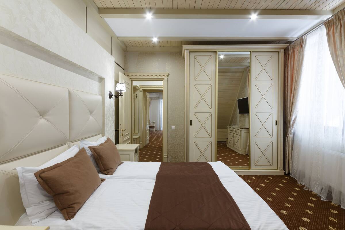 A hotel room with a large bed, a wardrobe, a mirror, and a bathroom visible through an open door.