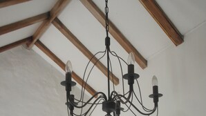 A chandelier with multiple bulbs and a rustic wooden beam below it.