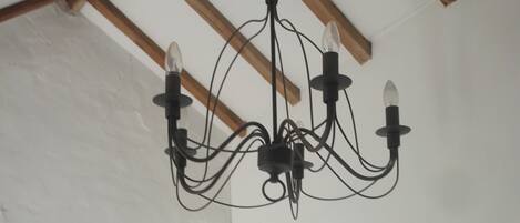 A chandelier with multiple bulbs and a rustic wooden beam below it.