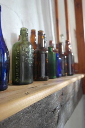 A wooden shelf with various colored glass bottles. - The Old Barn (Barry)