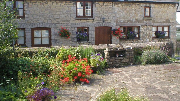 A stone building with multiple windows, some with shutters, and flower boxes on the windowsills.