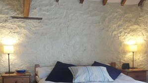 A bedroom with a wooden bed, two bedside tables, and a stone wall.