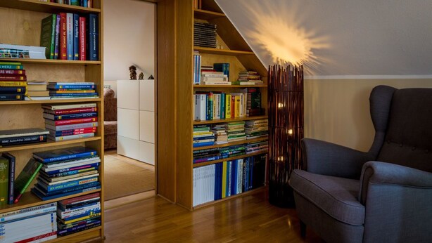 Un coin lecture confortable avec une bibliothèque, un fauteuil et une lampe.