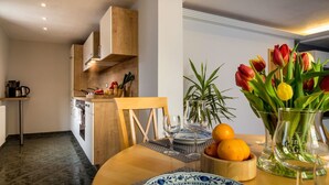 Une cuisine moderne avec des meubles en bois, une table à manger ornée d’un vase de tulipes, d’oranges et d’une carafe en verre.