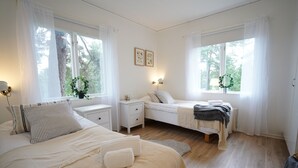 Een slaapkamer met een bed, nachtkastjes, en een raam met gordijnen.