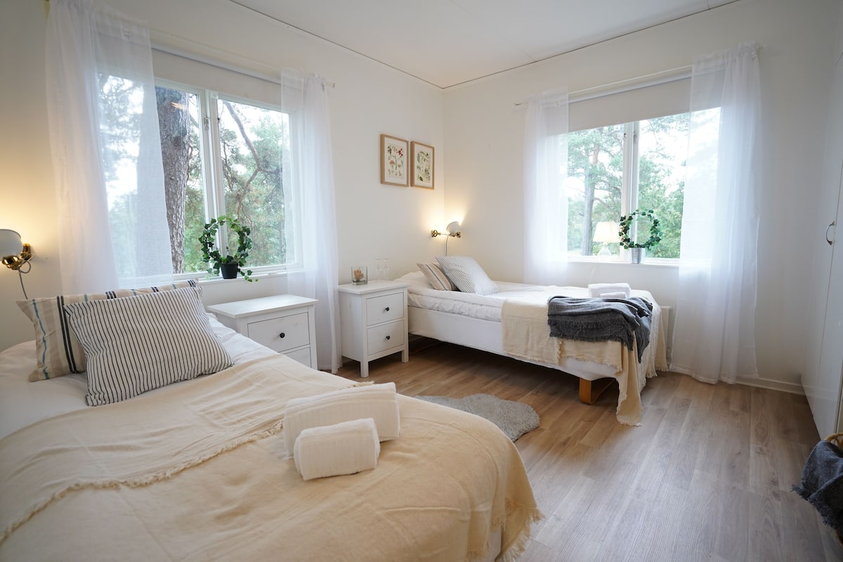 Een slaapkamer met een bed, nachtkastjes, en een raam met gordijnen.