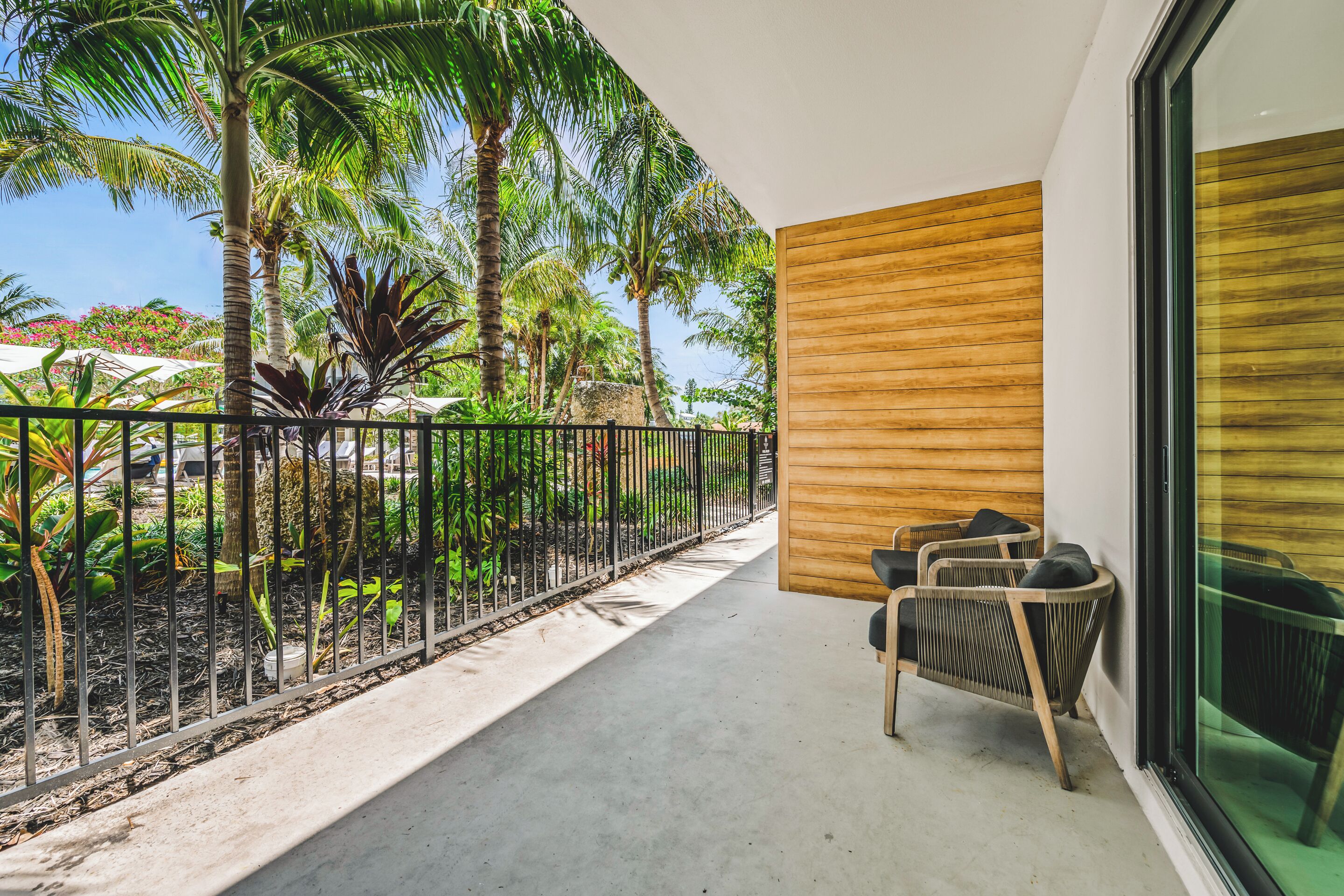 A balcony with a view of palm trees and a wooden wall.