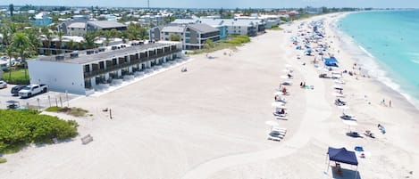 A beachfront hotel with multiple buildings, a sandy beach, and a clear view of the ocean.