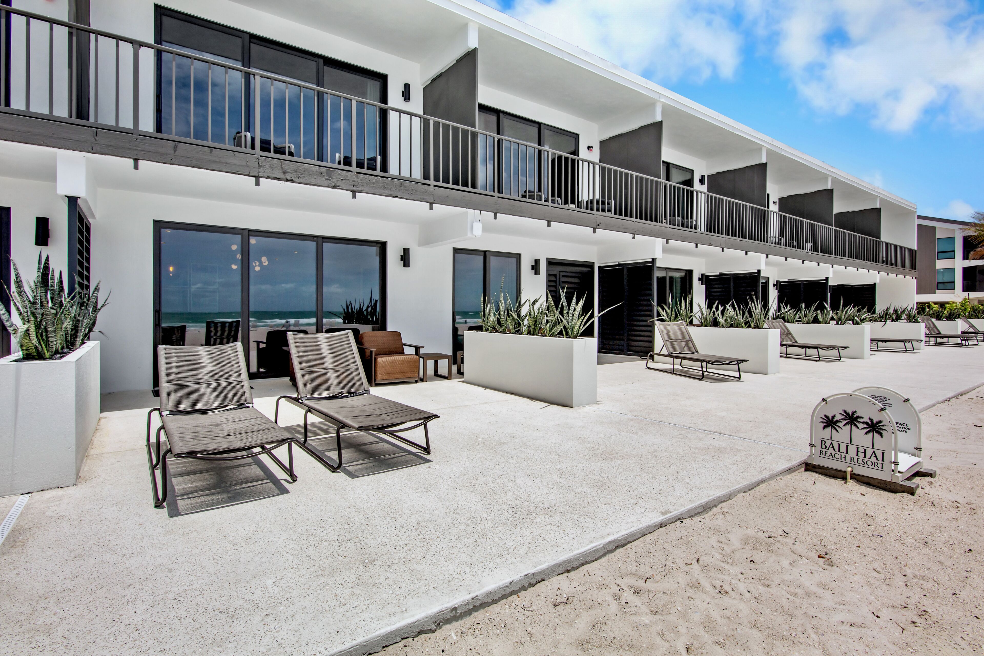 Un hotel modern amb balcó, mobiliari exterior i vista a l'oceà.
