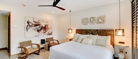 A spacious bedroom with a large bed, a ceiling fan, and a modern art piece on the wall.