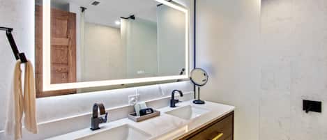 A modern bathroom with two sinks, a large mirror, and a vanity with drawers.