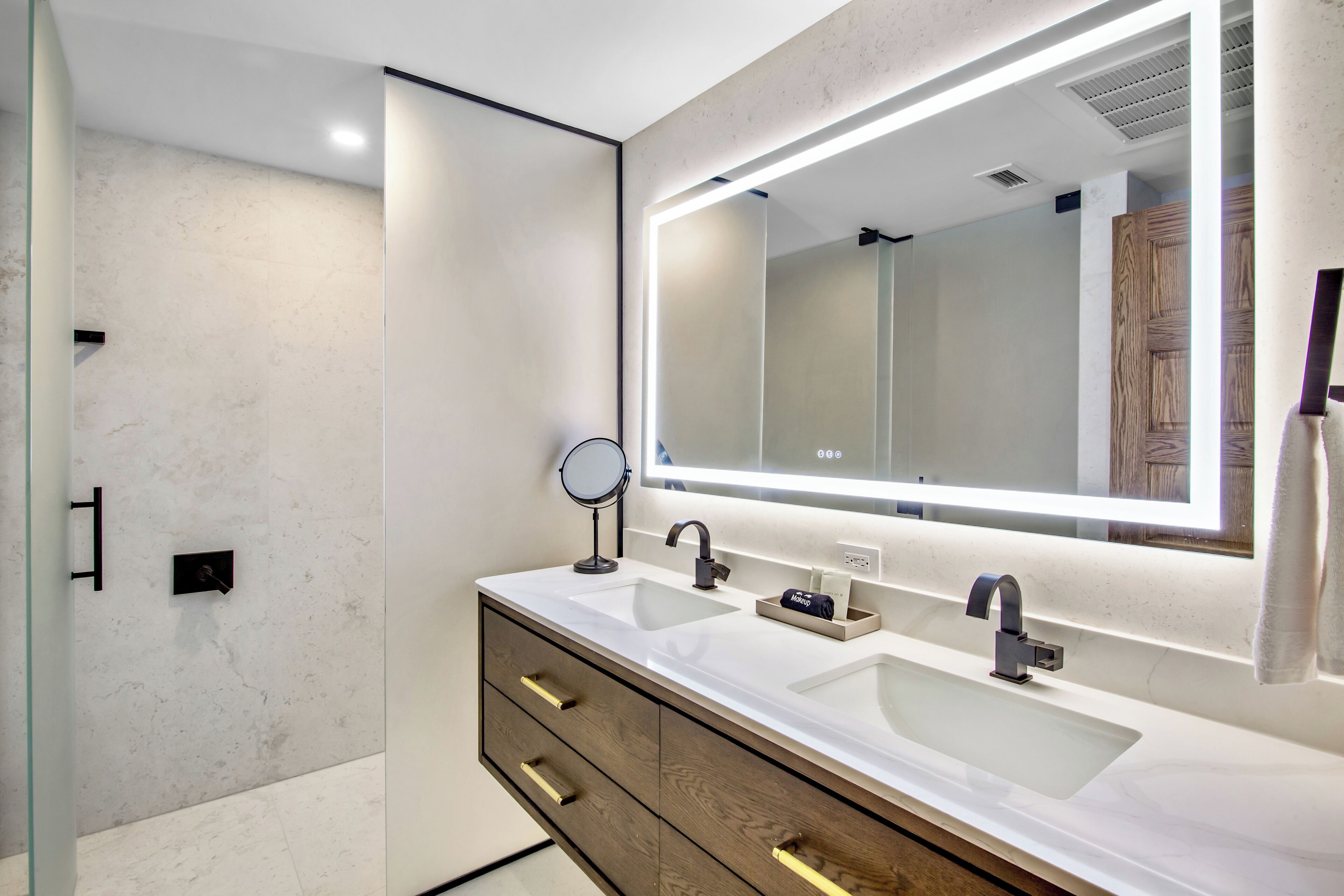 Un baño moderno con tocador doble, un espejo grande y cabina de ducha de vidrio.