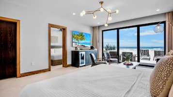 A modern hotel room with a large bed, a desk, and a view of the beach.