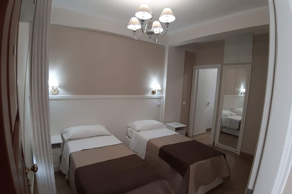 Habitación de hotel con dos camas, una mesita de noche, un espejo y un candelabro.