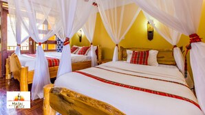 Una habitación con cuatro camas, cada una con ropa blanca y almohadas a cuadros rojos, bajo dosel blanco.