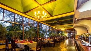 Un restaurante con mesas dispuestas para comer, una zona de bar y grandes ventanales que ofrecen vistas al exterior.