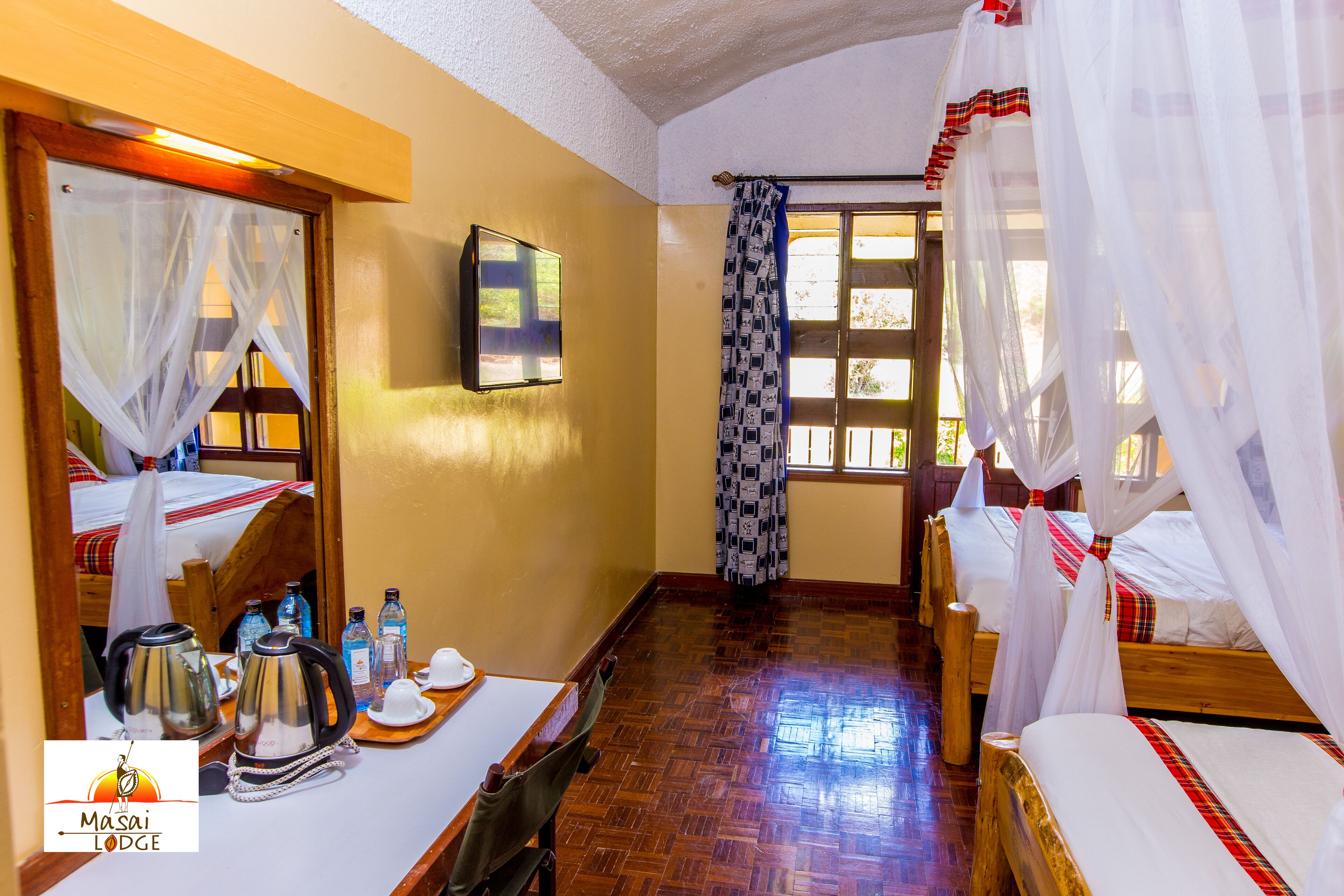 A room with two beds, a wooden floor, a television, and a window with curtains.