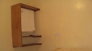 A bedroom with a bed, a wooden shelf, and a towel hanging on the wall.