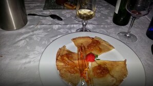 A plate with a dessert, a wine glass, and a bottle on a table.