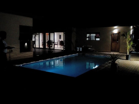 Una piscina al aire libre, sombrillas, sillones reclinables de piscina