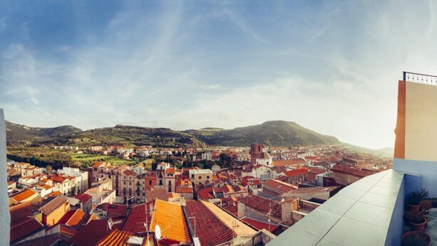 A panoramic view of a coastal town with red-roofed buildings and a mountain in the background. - B&B Blu Bosa (Bosa)