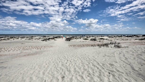 Una platja sorrenca amb dunes i un cel serè.