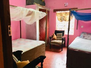 Un dormitorio con dos camas, una silla y una ventana con cortina.
