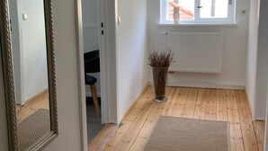 Una habitación con piso de madera, un espejo, un radiador y una ventana con persianas.