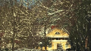 Un sendero cubierto de nieve que lleva a un edificio con fachada amarilla y una entrada central.