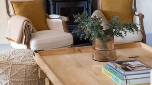 A cozy living room with a fireplace, two armchairs with cushions, a coffee table with books, and decorative plants. - Luxury 6-bed Tuscan Villa Near Lucca and Florence (Capannori)