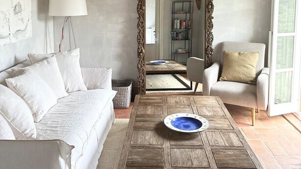 A living room with a wooden ceiling, a white sofa, a wooden coffee table, and a large mirror. - Luxury 6-bed Tuscan Villa Near Lucca and Florence (Capannori)