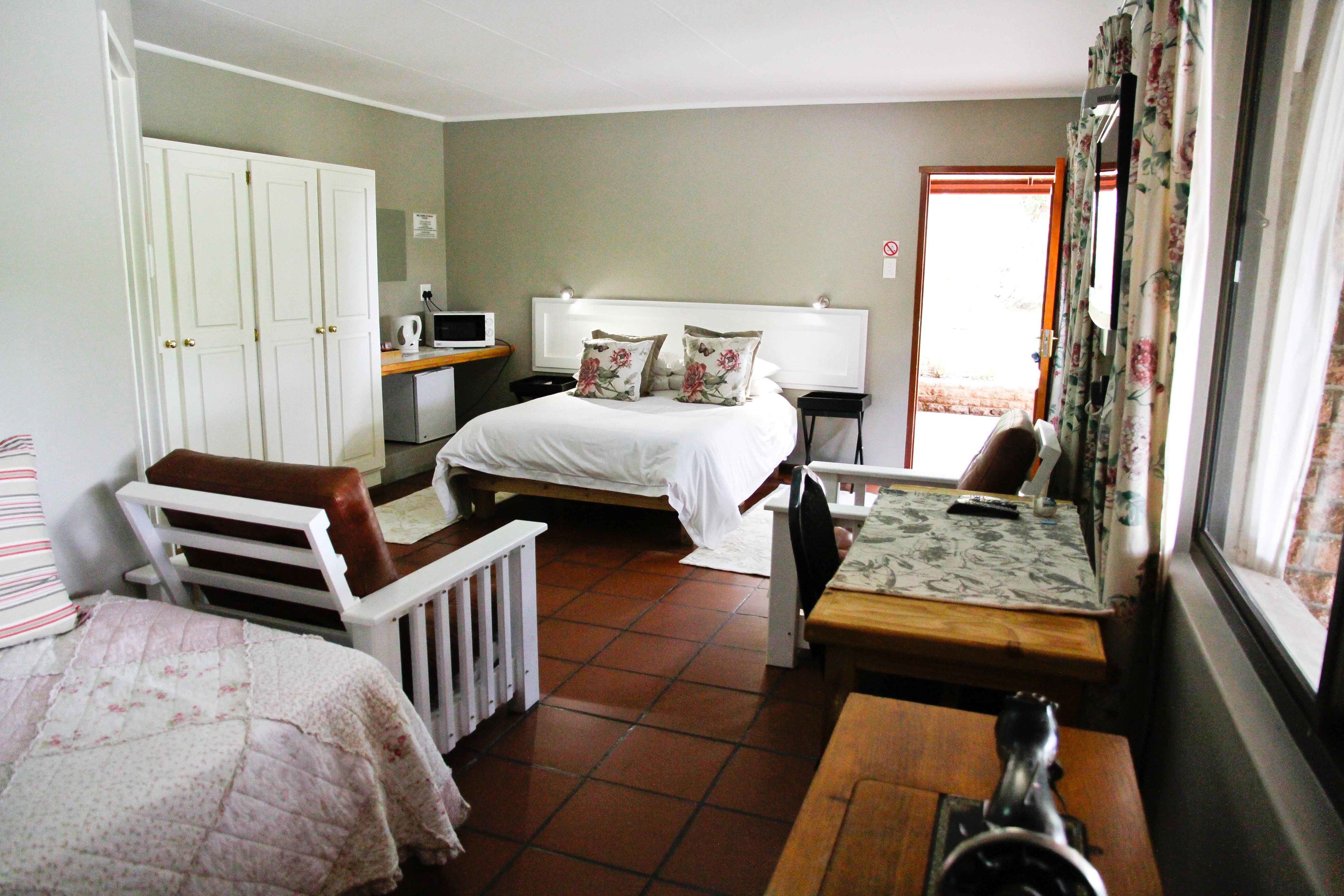 A bedroom with a bed, a desk, a chair, and a small table.
