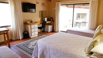 Een slaapkamer met twee bedden, een bureau, een stoel, een televisie en uitzicht op buiten.